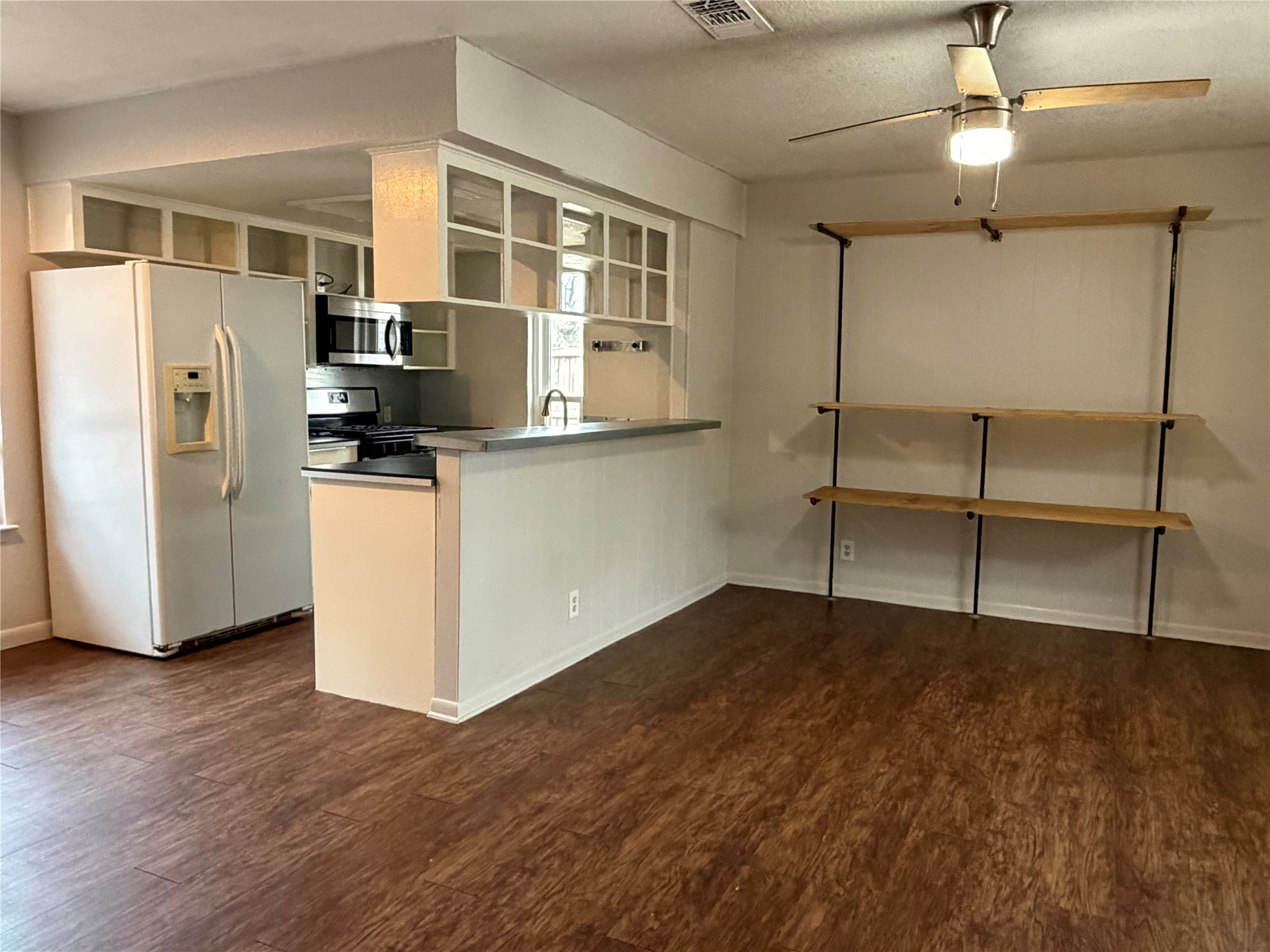 7404 Bethune Avenue, Unit B Austin, TX 78752 - Photo 4 of 13 Kitchen with stainless steel appliances, a ceiling fan, a peninsula, dark wood-type flooring, and a textured ceiling