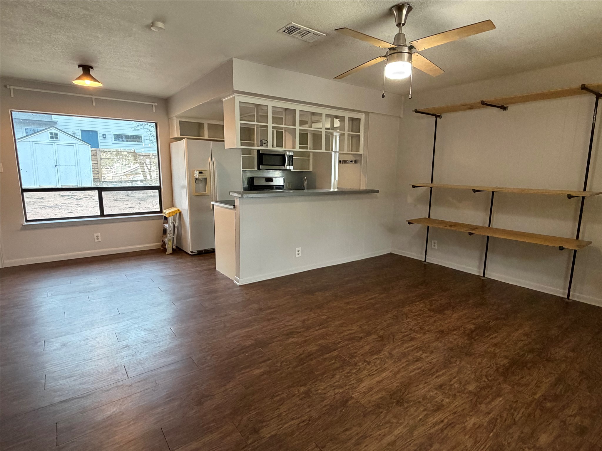 7404 Bethune Avenue, Unit B Austin, TX 78752 - Photo 5 of 13 Kitchen featuring a textured ceiling, stainless steel appliances, dark wood-type flooring, ceiling fan, and white cabinets