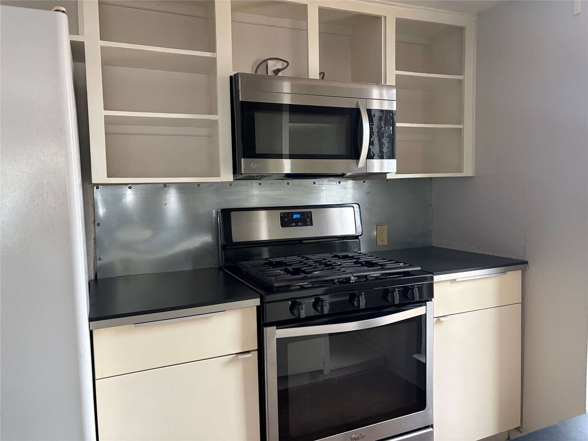 7404 Bethune Avenue, Unit B Austin, TX 78752 - Photo 8 of 13 Kitchen with stainless steel appliances, dark countertops, open shelves, and white cabinetry
