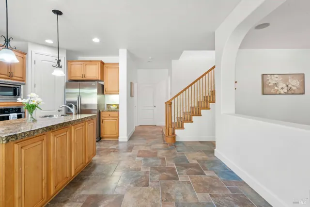 a kitchen with stainless steel appliances granite countertop a sink a stove a refrigerator a center island with wooden cabinets