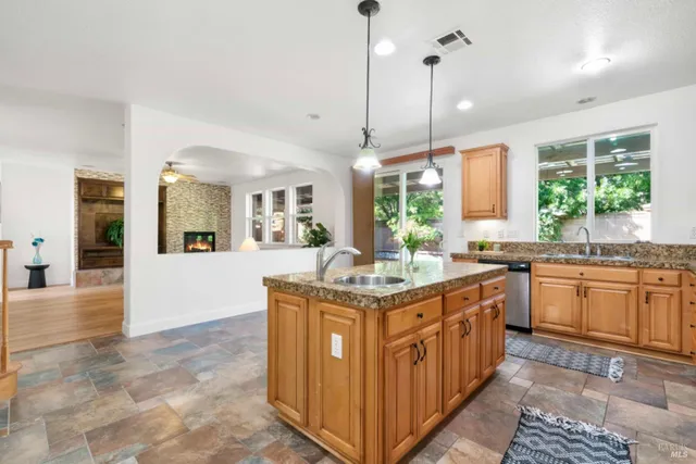 a kitchen with stainless steel appliances granite countertop a stove a sink dishwasher a refrigerator and white cabinets with wooden floor