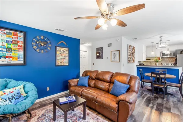 a living room with furniture kitchen view and a wooden floor