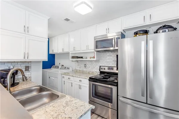 a kitchen with stainless steel appliances granite countertop a refrigerator sink and stove
