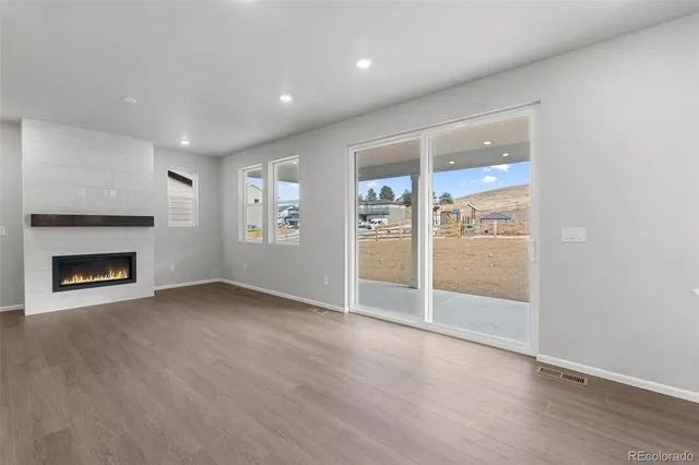 an empty room with wooden floor fireplace and windows