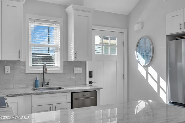 a kitchen with stainless steel appliances granite countertop a sink a stove and a window