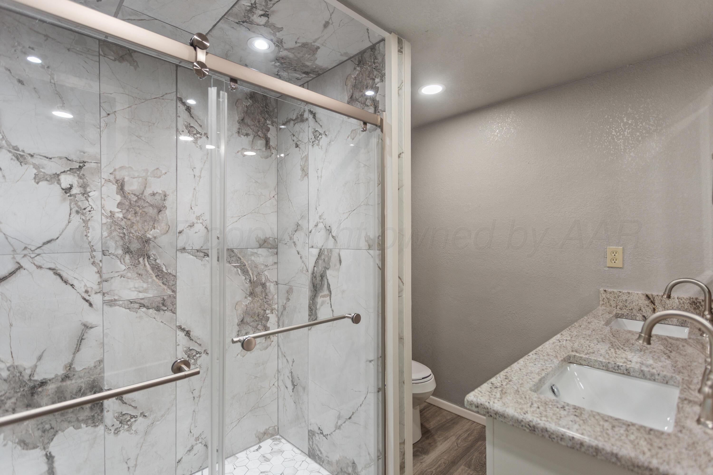 1119 South Main Street Wheeler, TX 79096 - Photo 31 of 49 a bathroom with a granite countertop sink mirror vanity and shower