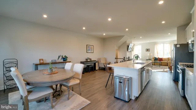 a living room with stainless steel appliances granite countertop furniture wooden floor and a view of kitchen