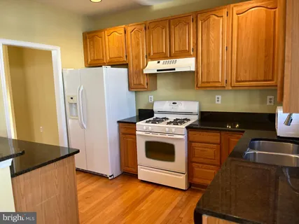 a kitchen with stainless steel appliances granite countertop a refrigerator a stove and a sink