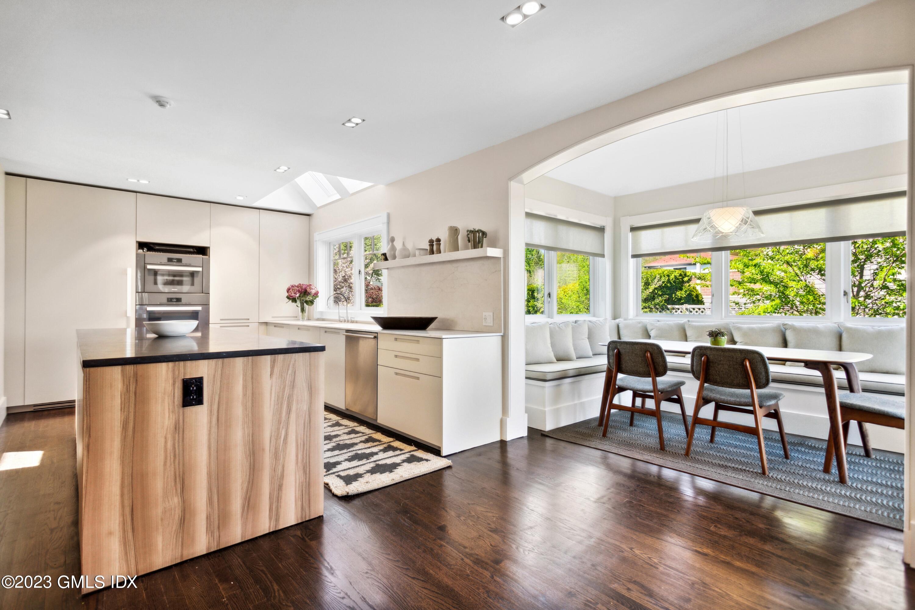 61 Byram Shore Road Greenwich, CT 06830 - Photo 12 of 36 a kitchen with stainless steel appliances granite countertop a refrigerator a stove top oven a dining table and chairs with wooden floor