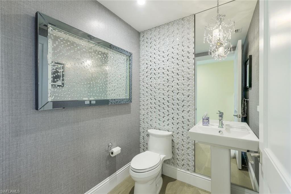 13665 Vanderbilt Drive, Unit 501 Naples, FL 34110 - Photo 22 of 45 a bathroom with a toilet sink and mirror