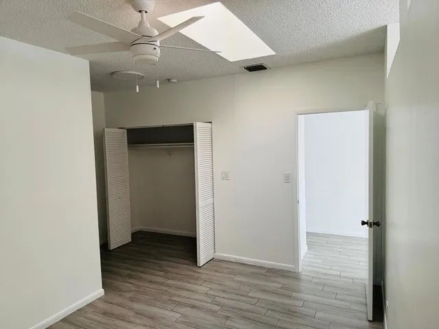 an empty room with wooden floor and ceiling fan