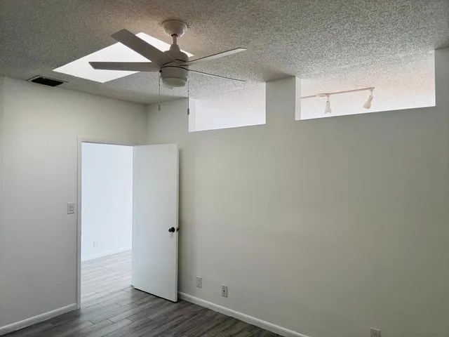 an empty room with wooden floor closet and windows