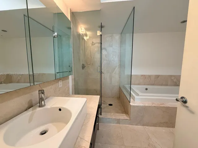 a bathroom with a tub shower sink and mirror