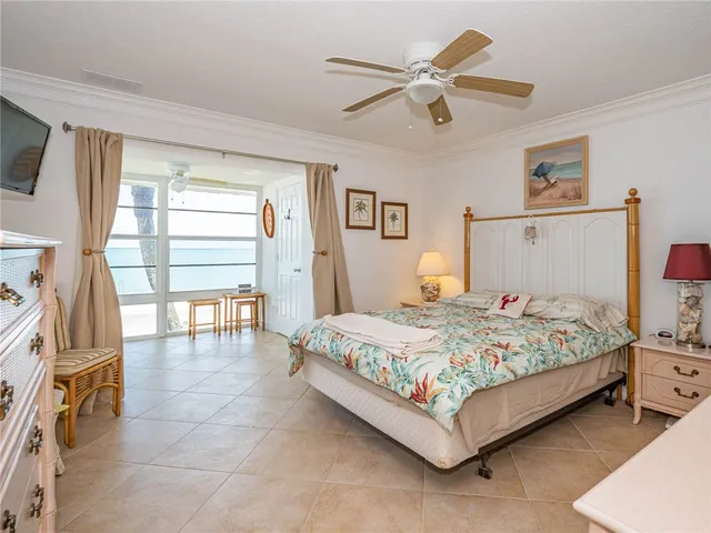 a bedroom with a bed a ceiling fan and a large window