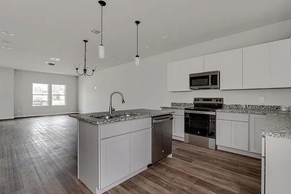 a kitchen with stainless steel appliances granite countertop a stove a sink and a microwave