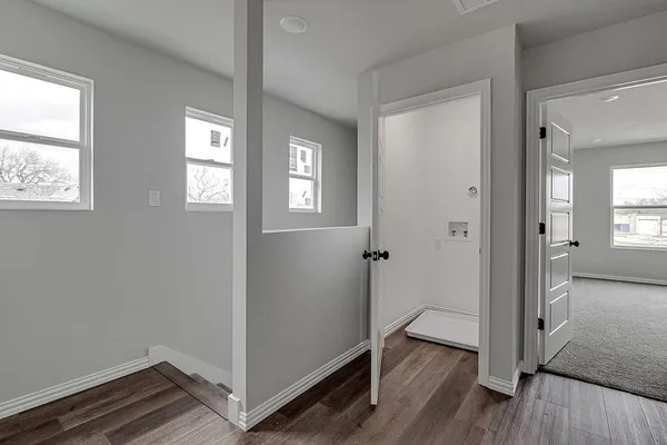 a view of hallway with window and wooden floor