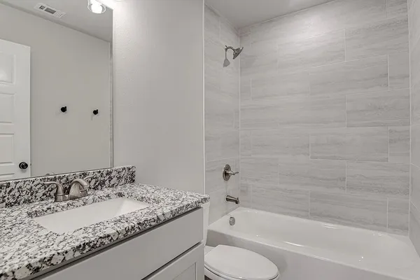 a bathroom with a granite countertop sink toilet and bathtub