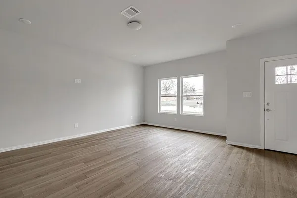 a view of an empty room with wooden floor and window