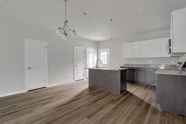 a kitchen with kitchen island white cabinets and wooden floor