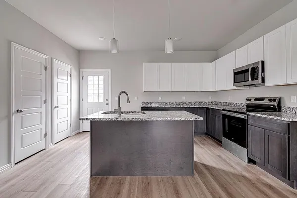 a kitchen with stainless steel appliances granite countertop a stove a sink dishwasher and a microwave oven with wooden floor