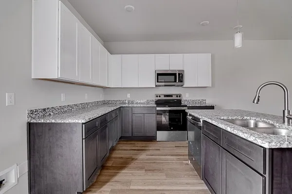 a kitchen with stainless steel appliances granite countertop a sink stove microwave and refrigerator