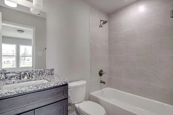 a bathroom with a granite countertop toilet a sink and a bathtub