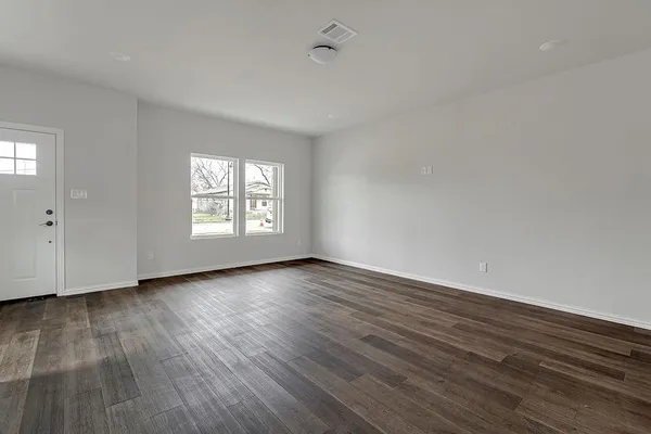 a view of an empty room with wooden floor and window