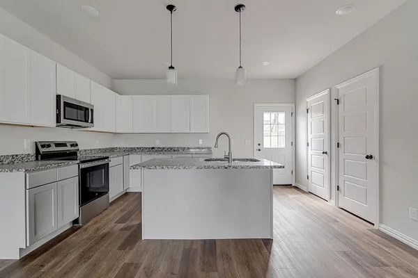 a large kitchen with stainless steel appliances granite countertop a stove a sink dishwasher and a refrigerator with wooden floor