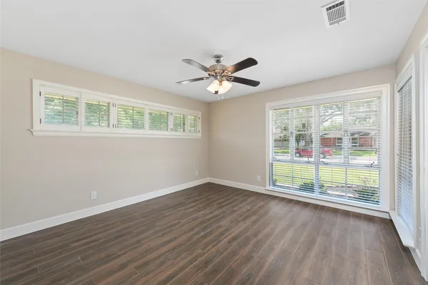 a view of an empty room with wooden floor and a window