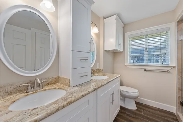 a bathroom with a granite countertop toilet a sink and a mirror