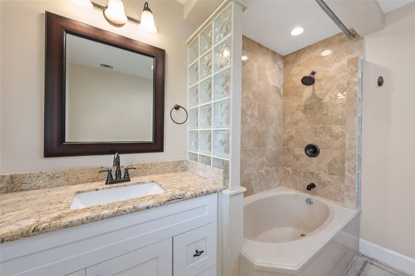 a bathroom with a granite countertop tub sink and mirror