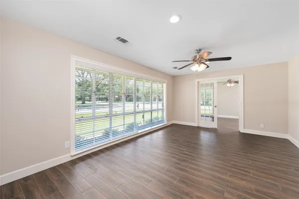a view of an empty room with wooden floor and a window