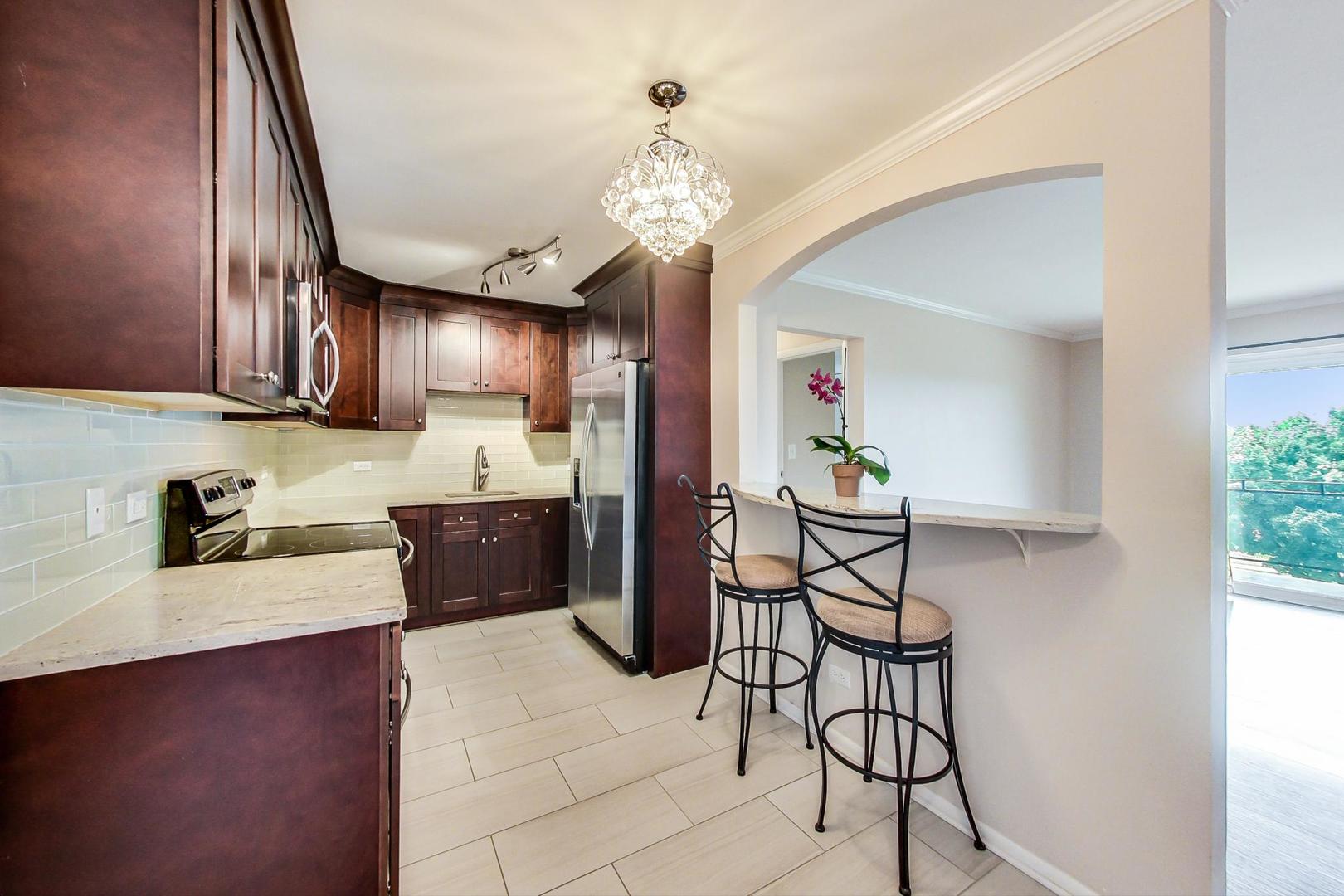 2234 South Goebbert Road, Unit 425 Arlington Heights, IL 60005 - Photo 4 of 20 a kitchen with stainless steel appliances granite countertop a refrigerator a sink dishwasher a dining table and chairs with wooden floor