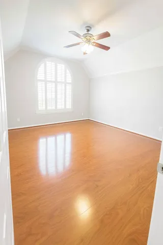 an empty room with wooden floor fan and windows