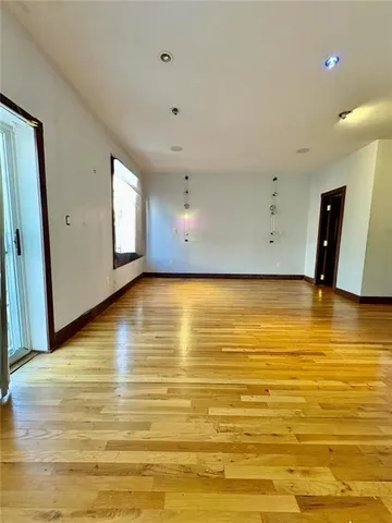 a view of an empty room with wooden floor and windows