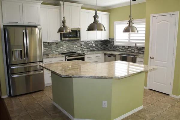 a kitchen with stainless steel appliances granite countertop a refrigerator a stove and a sink with wooden floor