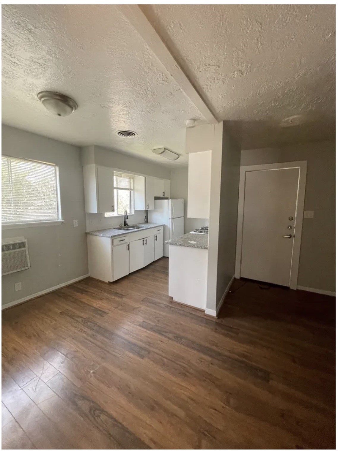 1014 East 23rd Street, Unit 3 Bryan, TX 77803 - Photo 3 of 8 an empty room with wooden floor kitchen view and windows