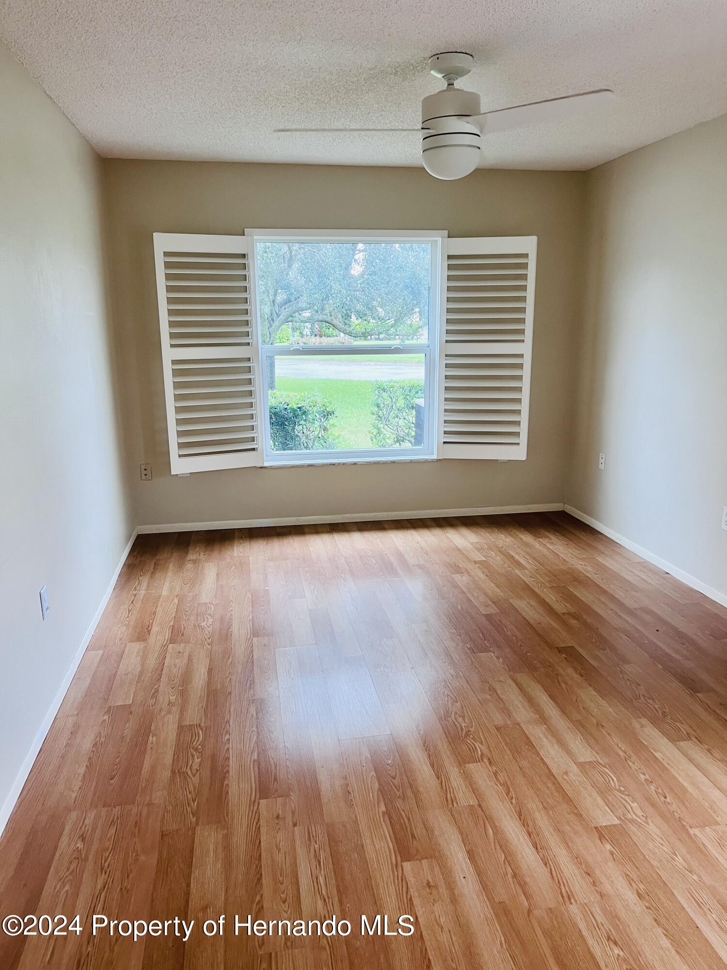 8141 Bugle Court Port Richey, FL 34668 - Photo 14 of 25 a view of an empty room with wooden floor and a window