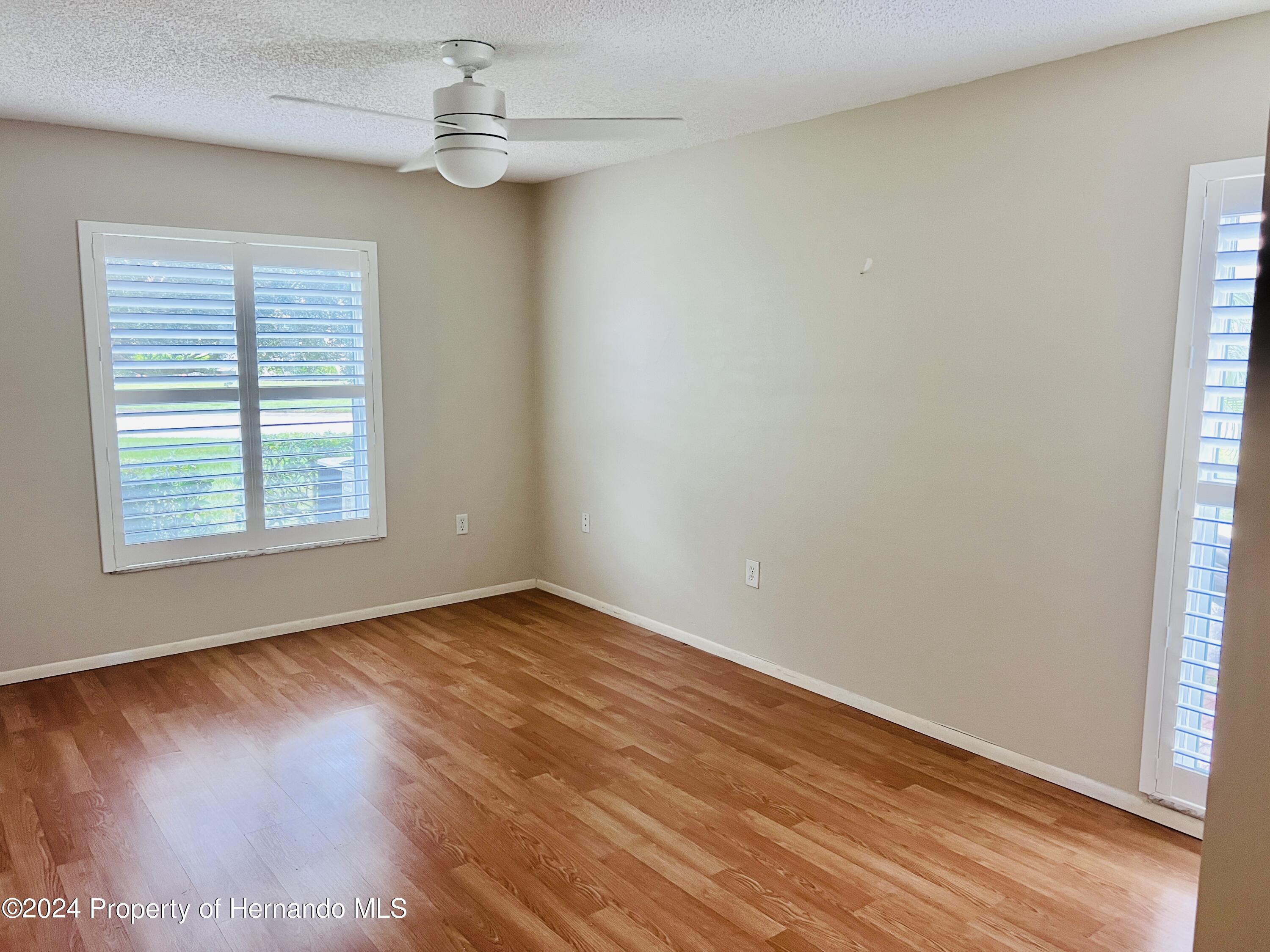 8141 Bugle Court Port Richey, FL 34668 - Photo 15 of 25 an empty room with wooden floor chandelier fan and windows