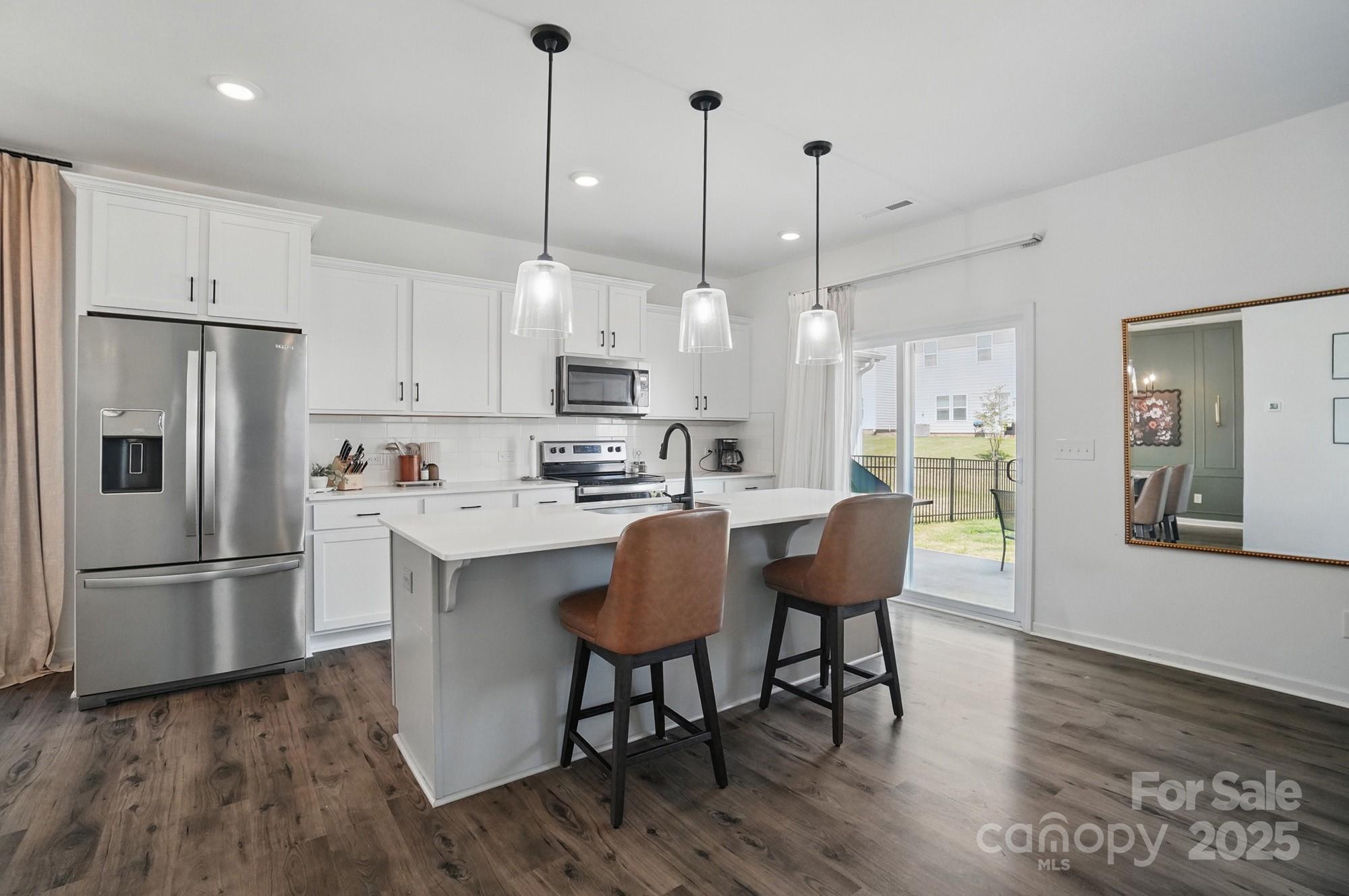 637 Scotch Meadows Loop Monroe, NC 28110 - Photo 7 of 30 a kitchen with stainless steel appliances granite countertop a refrigerator a sink a stove a dining table and chairs with wooden floor