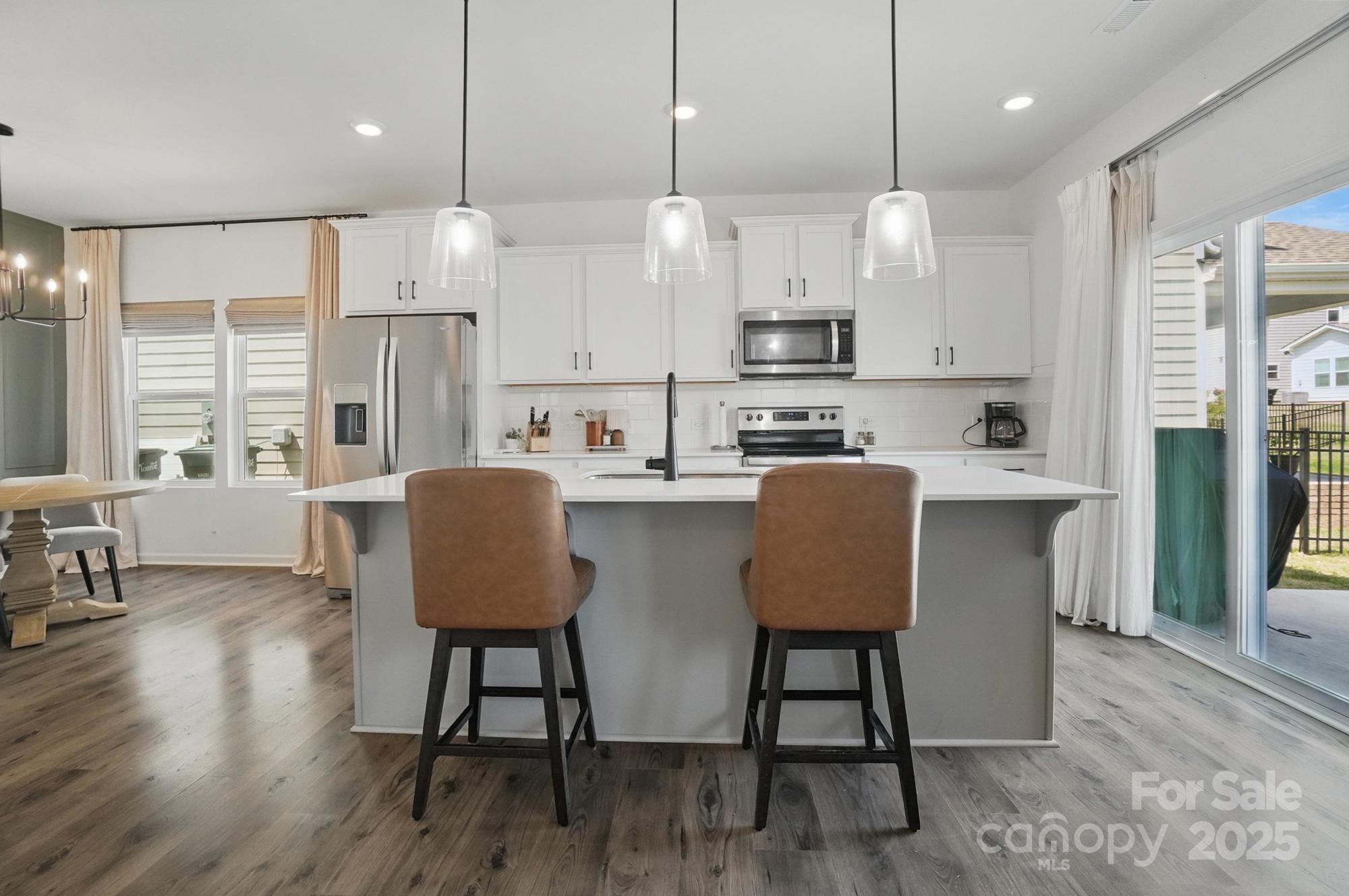 637 Scotch Meadows Loop Monroe, NC 28110 - Photo 8 of 30 a large kitchen with kitchen island a dining table chairs and a wooden floor