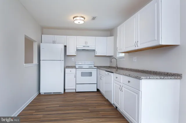 a kitchen with granite countertop a refrigerator sink and cabinets