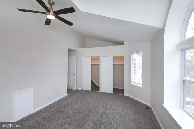an empty room with windows and fan