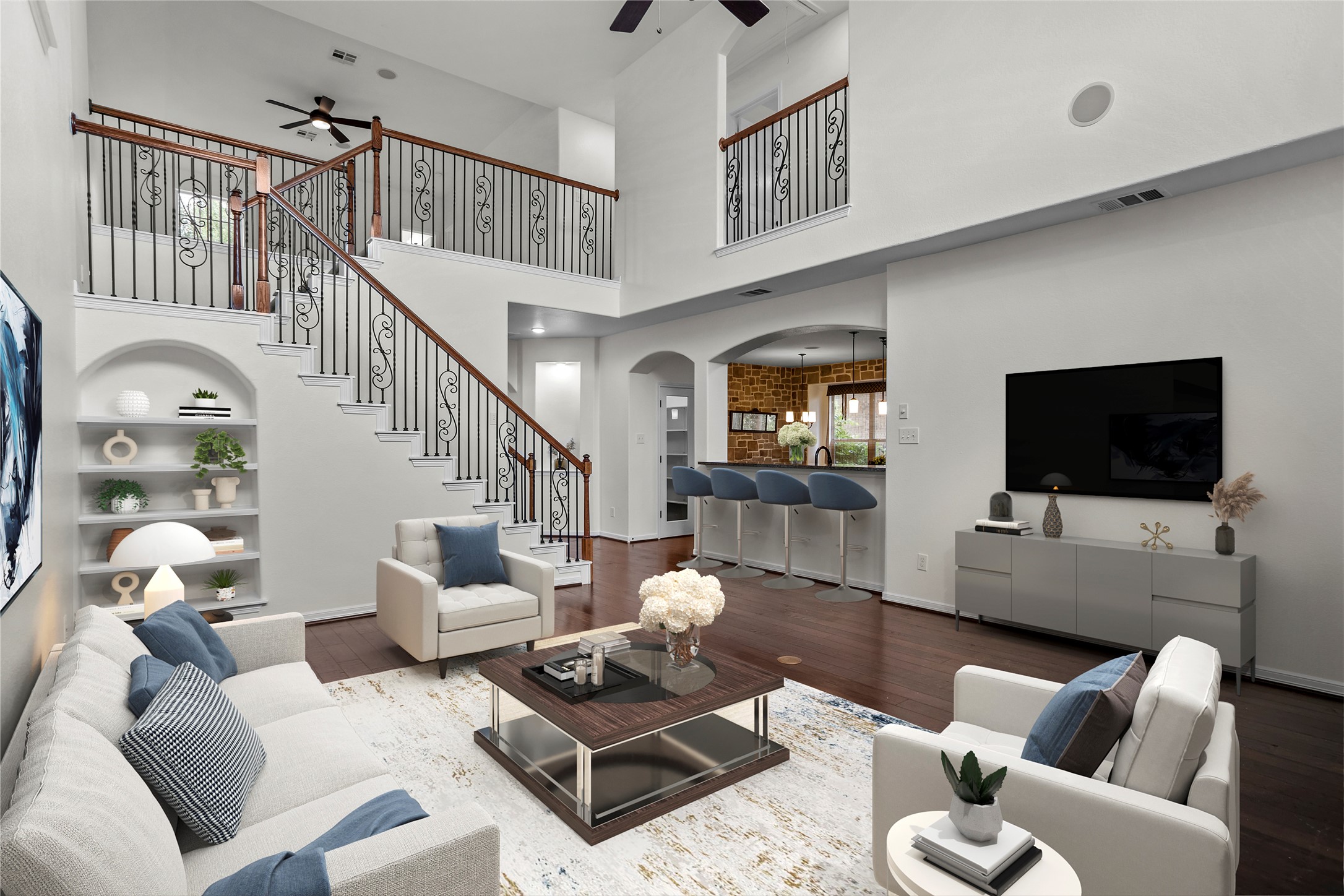 245 Razzmatazz Trail Buda, TX 78610 - Photo 14 of 37 Two-story living area featuring wood-finish flooring, a grand staircase with wrought iron balusters and wood handrails, and an arched built-in shelving unit