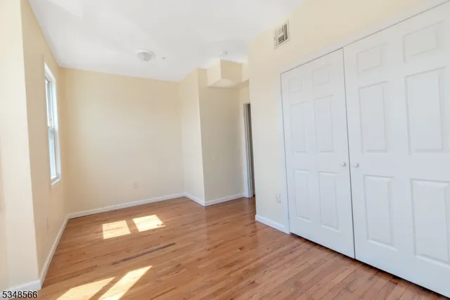 a view of an empty room with wooden floor and closet