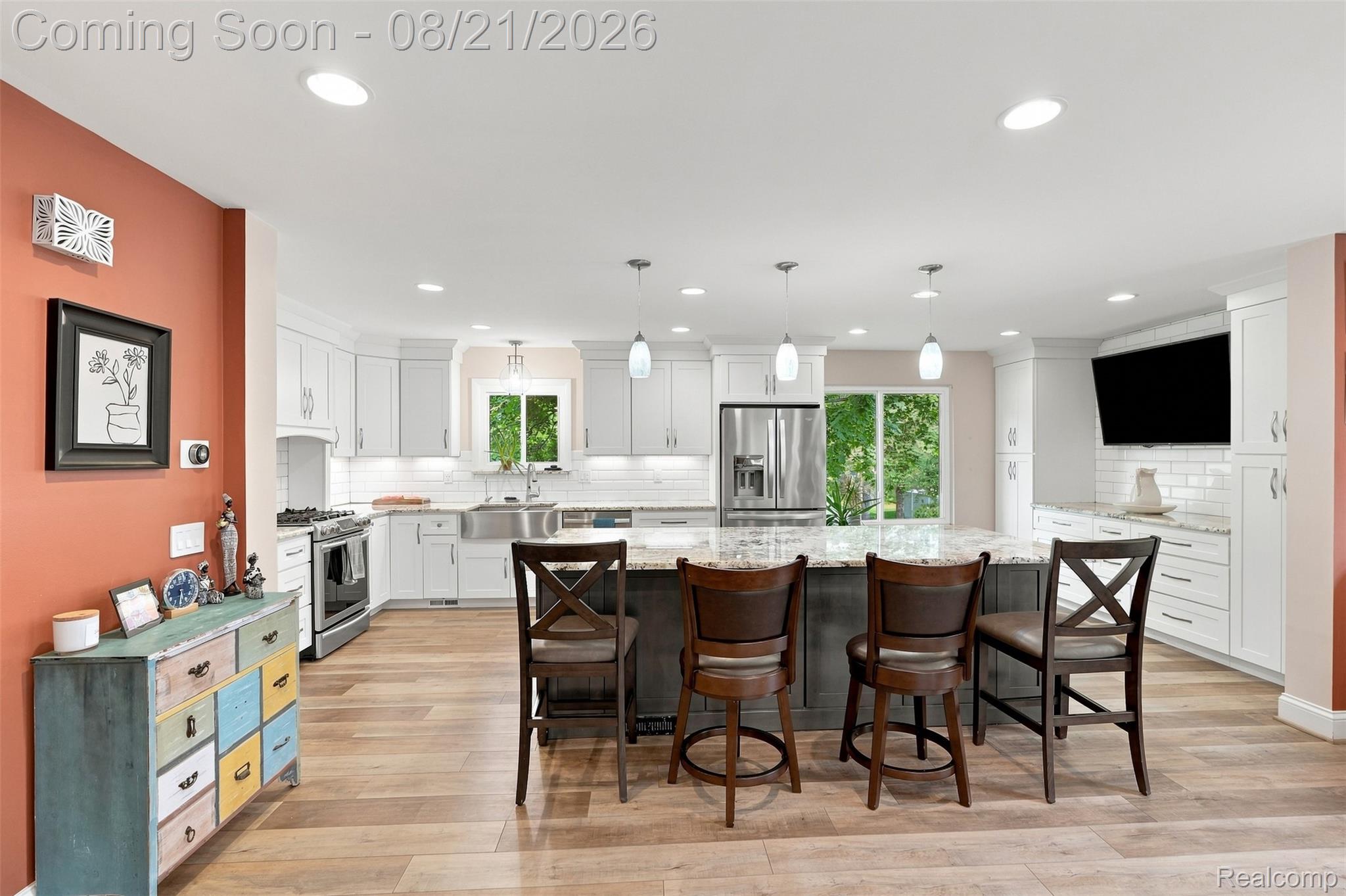 6060 Ford Road Commerce Township, MI 48382 - Photo 9 of 58 Gourmet kitchen featuring a large island with seating, stainless steel appliances, white cabinetry, wood-finish flooring, and recessed lighting