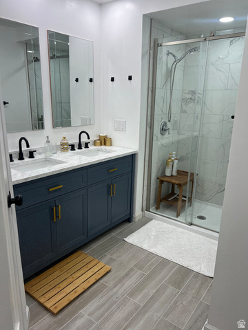2807 North Ogden Canyon Road Eden, UT 84310 - Photo 23 of 72 Modern bathroom featuring a dual vanity with a quartz countertop and navy cabinetry, a glass-enclosed shower with white marble-look tile, and wood-finish tile flooring