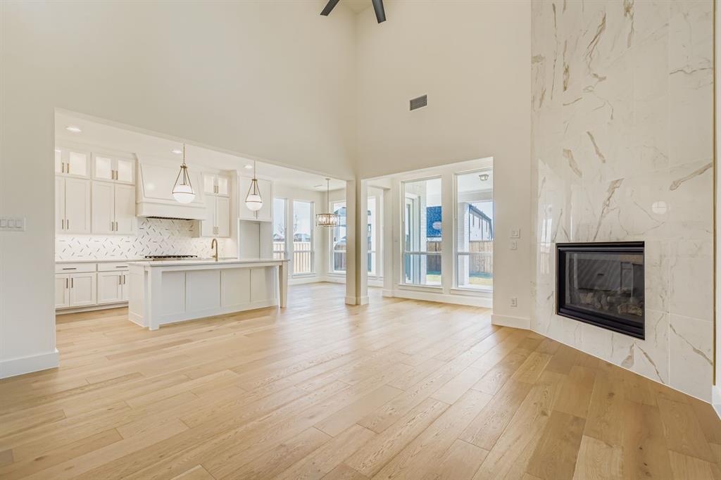 2651 Merrell Court Prosper, TX 75078 - Photo 4 of 28 a large white kitchen with a fireplace and wooden floor