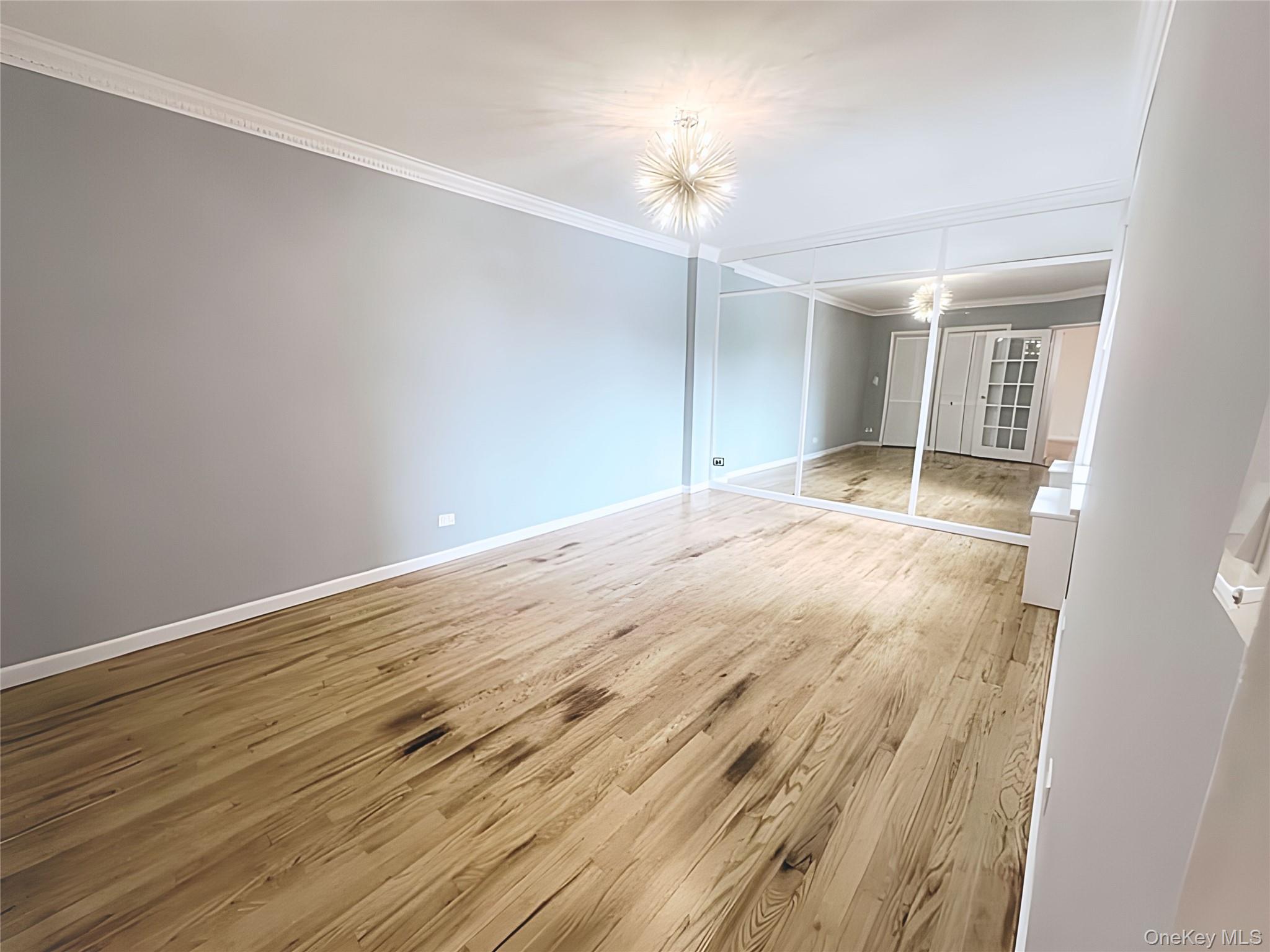 800 Grand Concourse, Unit 2JS Bronx, NY 10451 - Photo 8 of 18 an empty room with wooden floor and chandelier fan