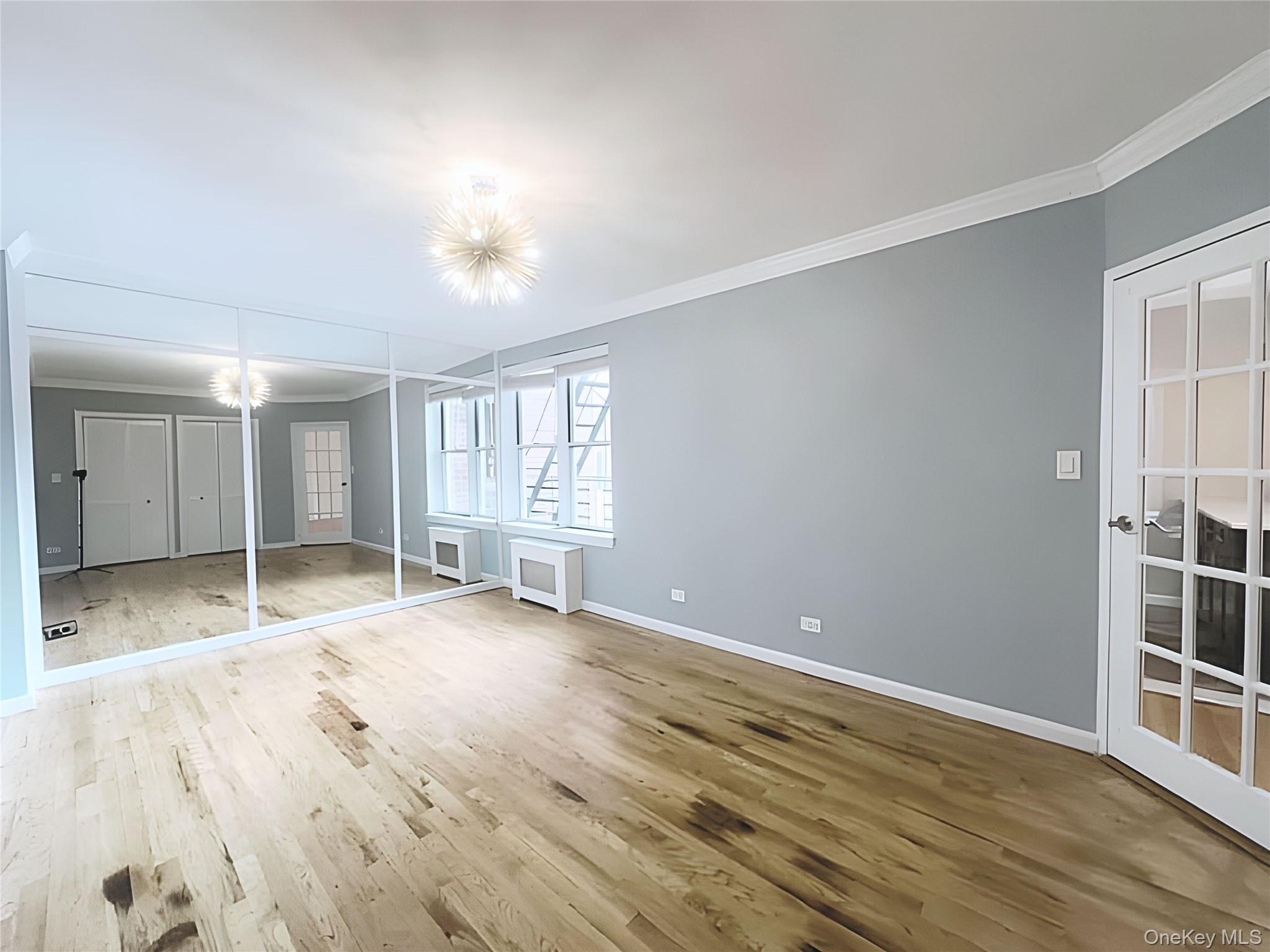 800 Grand Concourse, Unit 2JS Bronx, NY 10451 - Photo 9 of 18 a view of an empty room with wooden floor and kitchen